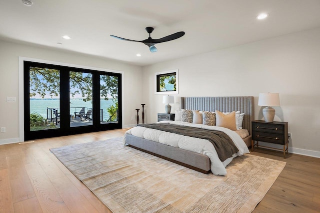 bedroom with access to outside, ceiling fan, a water view, and light hardwood / wood-style floors