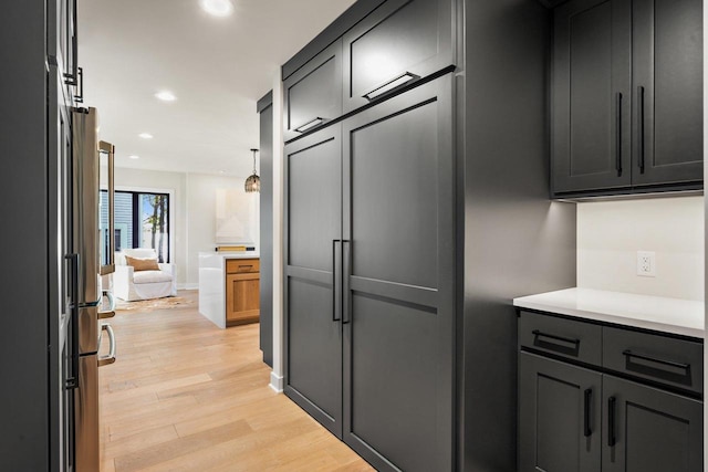 kitchen featuring stainless steel fridge, hanging light fixtures, and light hardwood / wood-style floors