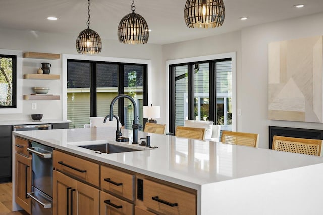 kitchen with a breakfast bar, sink, an island with sink, light hardwood / wood-style floors, and a chandelier