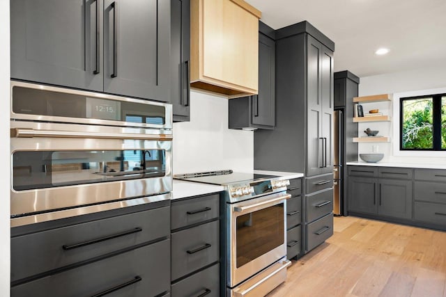 kitchen featuring gray cabinetry, light wood-type flooring, and appliances with stainless steel finishes