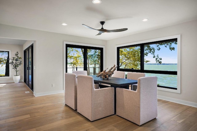 dining space with a water view, hardwood / wood-style flooring, and ceiling fan