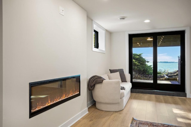 sitting room with a water view and light hardwood / wood-style floors