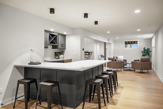 kitchen featuring kitchen peninsula, light wood-type flooring, and a breakfast bar area