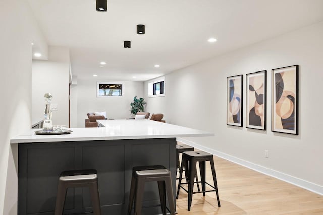 kitchen with light hardwood / wood-style floors, a kitchen bar, and kitchen peninsula