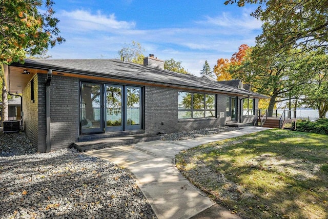 2291 Williams Point Dr, Stoughton, WI 53589 - rear view of property featuring brick siding, a chimney, central air condition unit, and a yard
