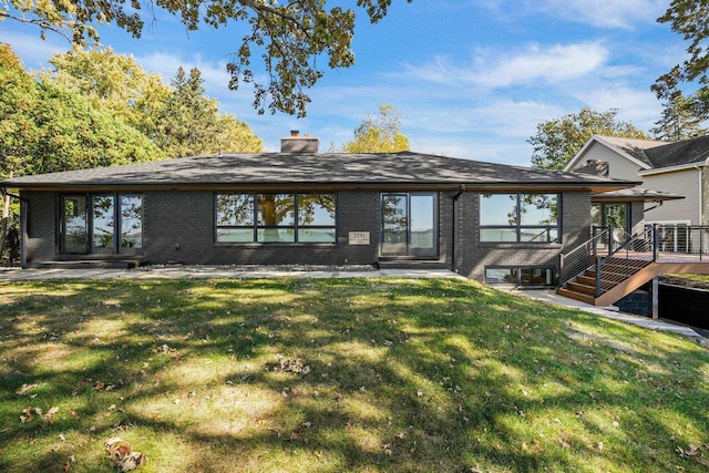 rear view of property with a deck and a lawn