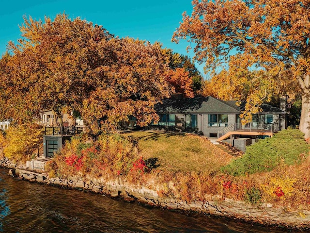 back of property with a yard and a water view