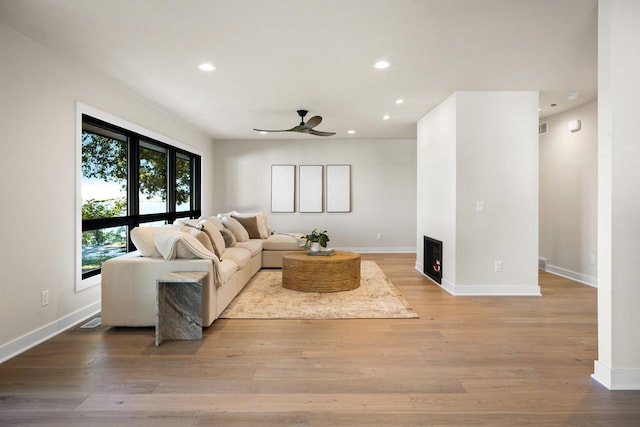 living room with ceiling fan and light hardwood / wood-style flooring