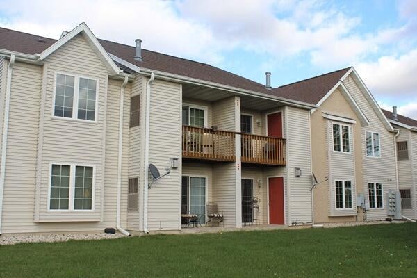 back of house with a yard and a balcony