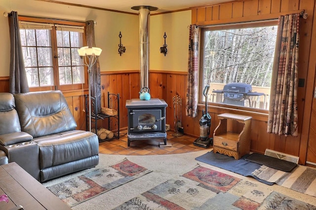 living area featuring light tile patterned floors, crown molding, a wood stove, and wood walls