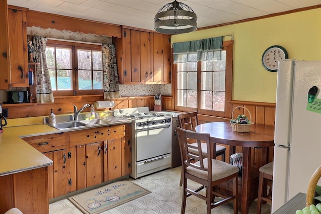 kitchen with white appliances, ornamental molding, sink, and decorative light fixtures