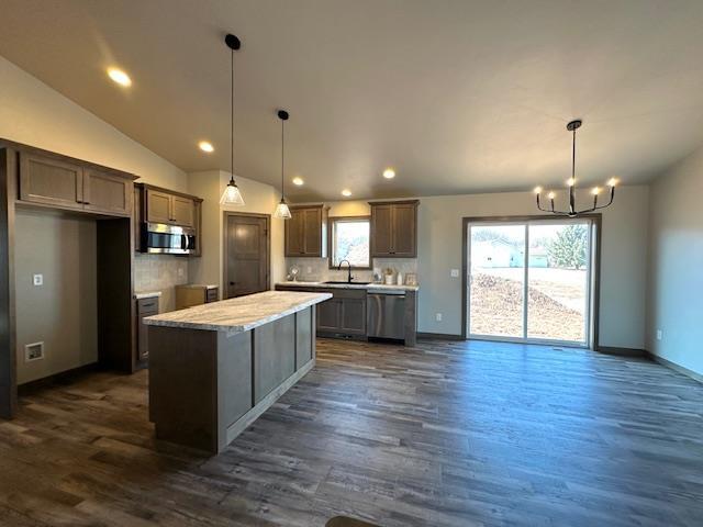 kitchen with a sink, stainless steel appliances, a center island, and vaulted ceiling