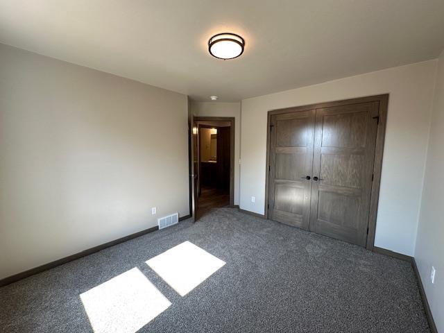 unfurnished bedroom with visible vents, baseboards, a closet, and carpet flooring