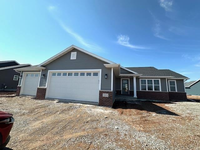 ranch-style home featuring a garage, brick siding, and dirt driveway