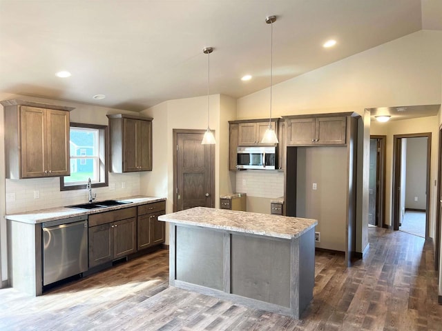 kitchen featuring dark wood-style floors, lofted ceiling, a sink, appliances with stainless steel finishes, and pendant lighting