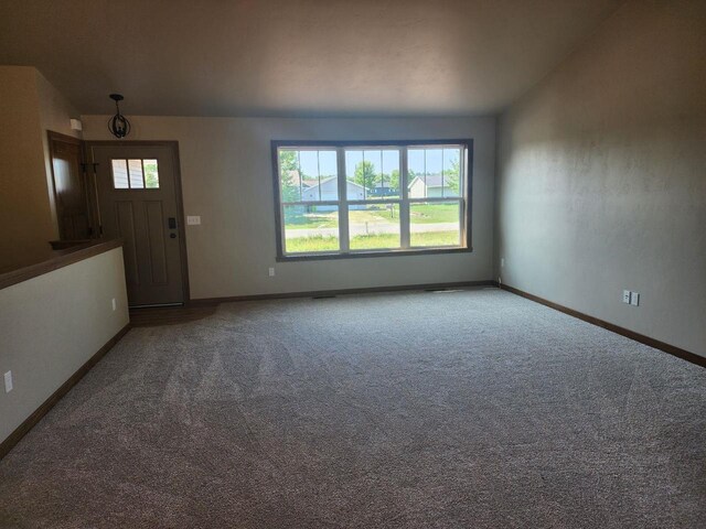 unfurnished living room featuring baseboards and carpet floors