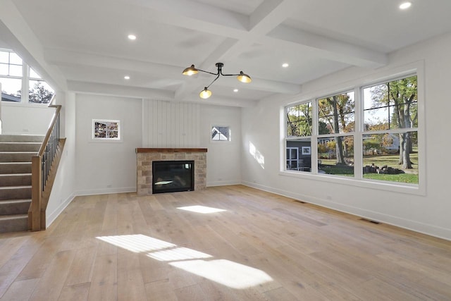 unfurnished living room with light hardwood / wood-style flooring, beam ceiling, coffered ceiling, and a fireplace