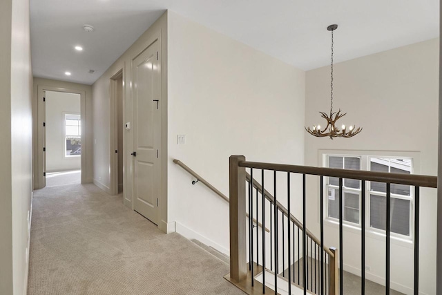 hallway featuring light carpet and an inviting chandelier