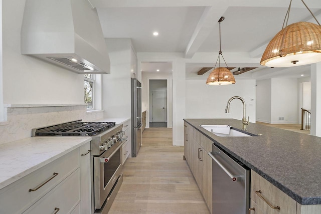 kitchen featuring appliances with stainless steel finishes, sink, an island with sink, light hardwood / wood-style floors, and wall chimney exhaust hood