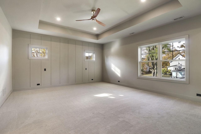 carpeted spare room with ceiling fan and a tray ceiling