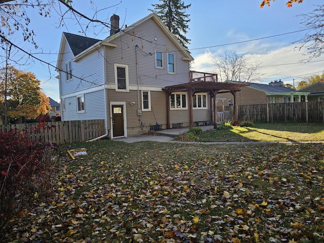 back of property with a pergola, a lawn, and a patio area