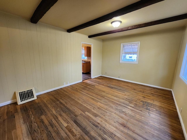 spare room featuring hardwood / wood-style flooring, beamed ceiling, and wood walls