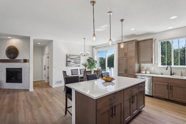 kitchen with stainless steel dishwasher, a breakfast bar, hanging light fixtures, and plenty of natural light