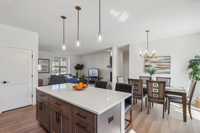 kitchen with a kitchen island, light hardwood / wood-style flooring, a kitchen bar, and decorative light fixtures