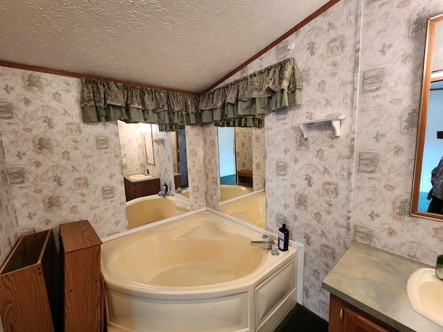 bathroom featuring a tub, crown molding, vaulted ceiling, vanity, and a textured ceiling