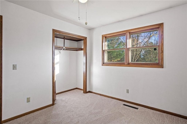 unfurnished bedroom with a closet and light colored carpet