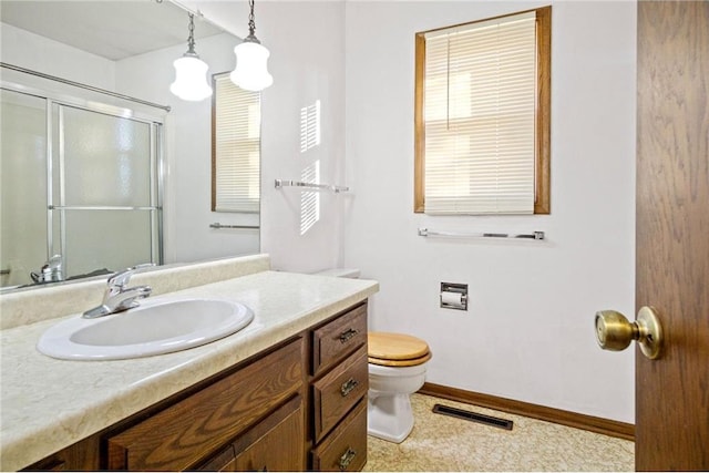 bathroom featuring vanity, toilet, and a shower with door