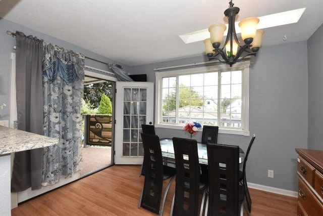 dining area featuring an inviting chandelier, hardwood / wood-style flooring, and a skylight