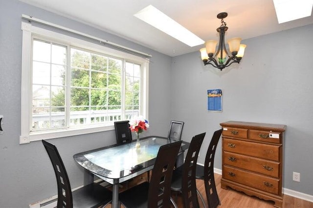 dining space with light hardwood / wood-style floors, a baseboard heating unit, and a chandelier