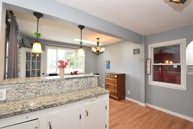 kitchen with white cabinets, a chandelier, light wood-type flooring, and pendant lighting