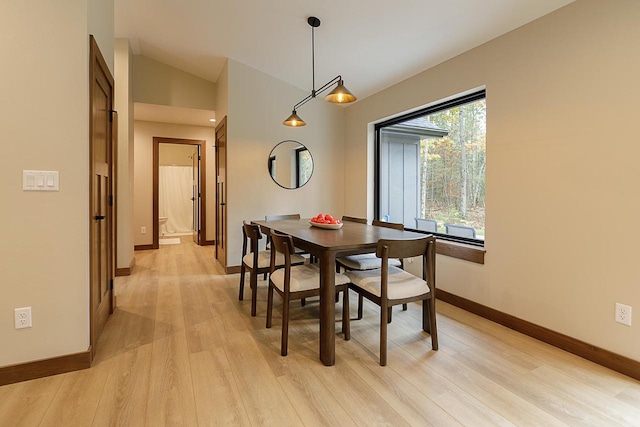 dining area with light hardwood / wood-style floors and vaulted ceiling