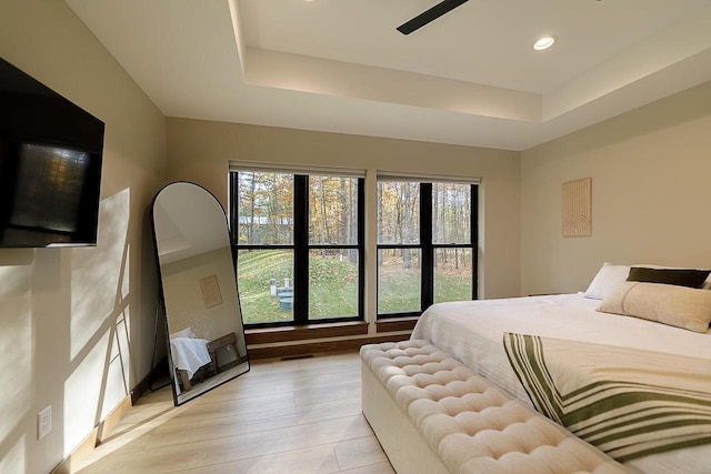 bedroom with a tray ceiling, light wood-type flooring, and ceiling fan