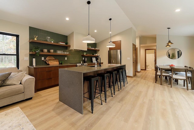 bar featuring light hardwood / wood-style floors, tasteful backsplash, stainless steel refrigerator, and vaulted ceiling