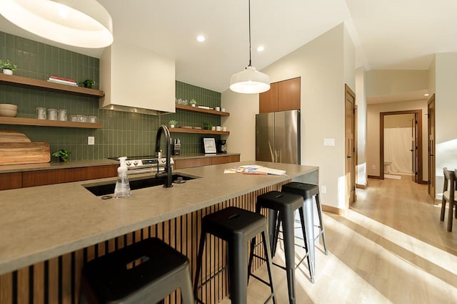 kitchen featuring a breakfast bar area, lofted ceiling, stainless steel fridge, and backsplash