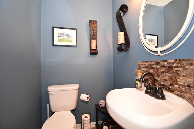 bathroom featuring toilet, decorative backsplash, and sink