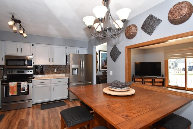 kitchen featuring white cabinetry, tasteful backsplash, stainless steel appliances, and hanging light fixtures