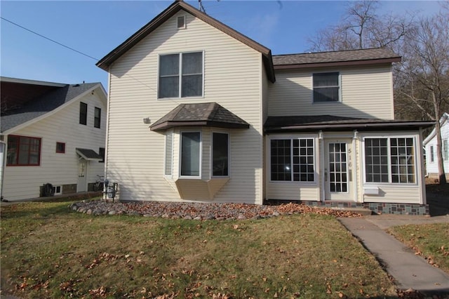 rear view of property featuring a yard and a sunroom