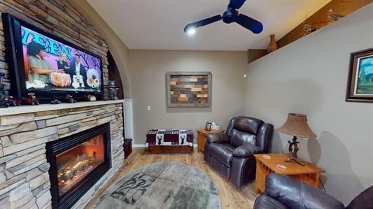 living room featuring a fireplace, light hardwood / wood-style floors, and ceiling fan