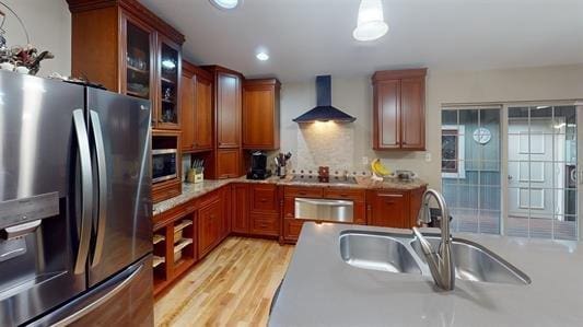 kitchen with sink, wall chimney range hood, cooktop, stainless steel fridge with ice dispenser, and light hardwood / wood-style flooring