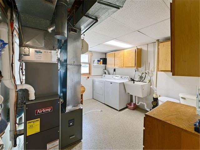 laundry room with washing machine and dryer, heating unit, cabinets, and sink