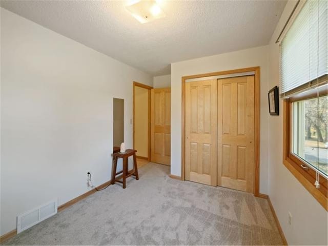 unfurnished bedroom featuring light carpet and a closet