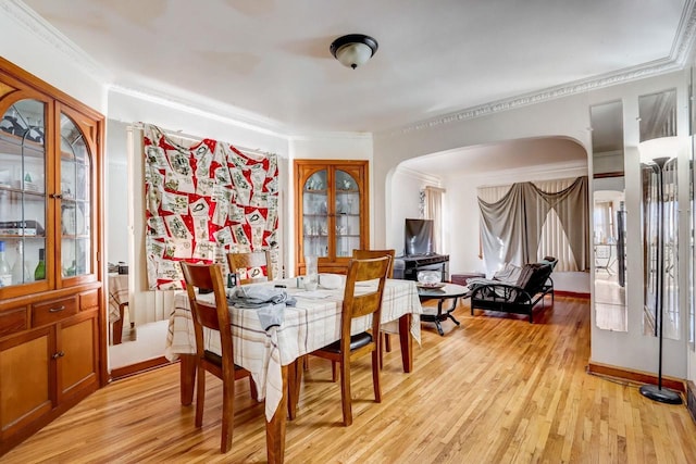 dining space with ornamental molding and light hardwood / wood-style floors