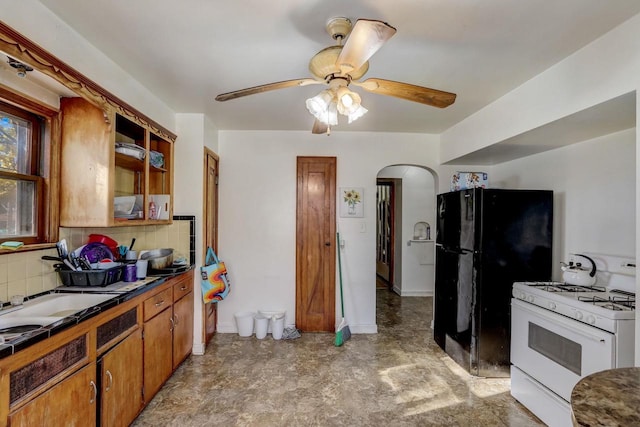 kitchen featuring black fridge, tasteful backsplash, ceiling fan, and gas range gas stove