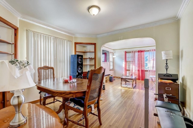 dining area with crown molding, built in shelves, and light wood-type flooring