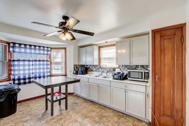 kitchen with tasteful backsplash, white cabinetry, sink, and ceiling fan