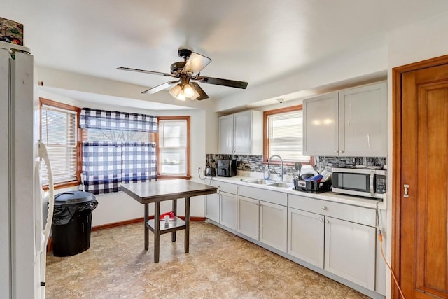 kitchen featuring tasteful backsplash, sink, white cabinets, and ceiling fan